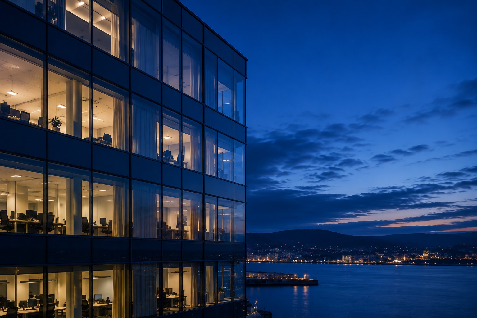 A lit office building facade at dusk, overlooking the water